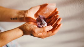 Young woman holding crystals, trying to find the tarot card that best represents her, per her zodiac...
