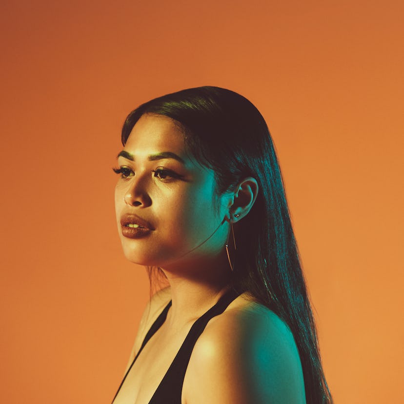 Young woman in front of an orange wall, wondering what Chiron means in astrology.