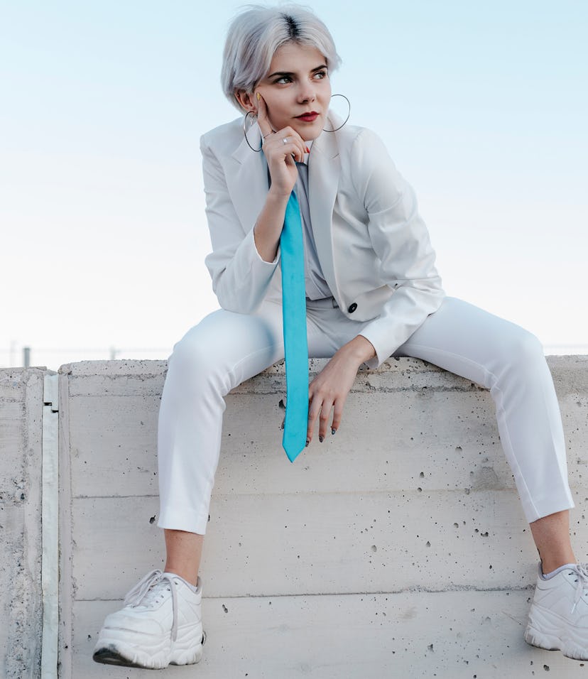 Young nonbinary individual with a blue tie wondering how they have all 12 zodiac signs in their birt...