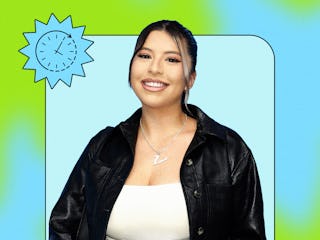 A smiling woman wearing a black jacket and white top stands in front of a light blue background, fra...