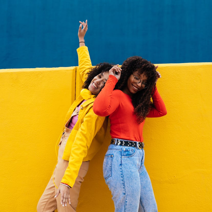 two women dance and smile together as they think about whether or not their sign is compatible with ...