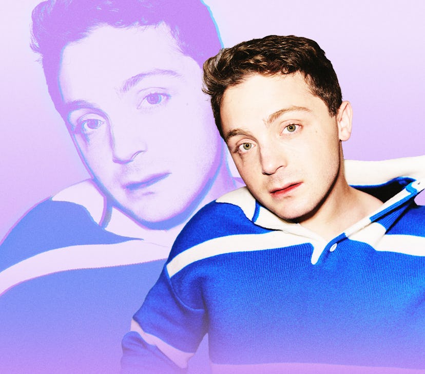 A person with short, curly hair and a blue striped sweater poses against a soft pink background, wit...